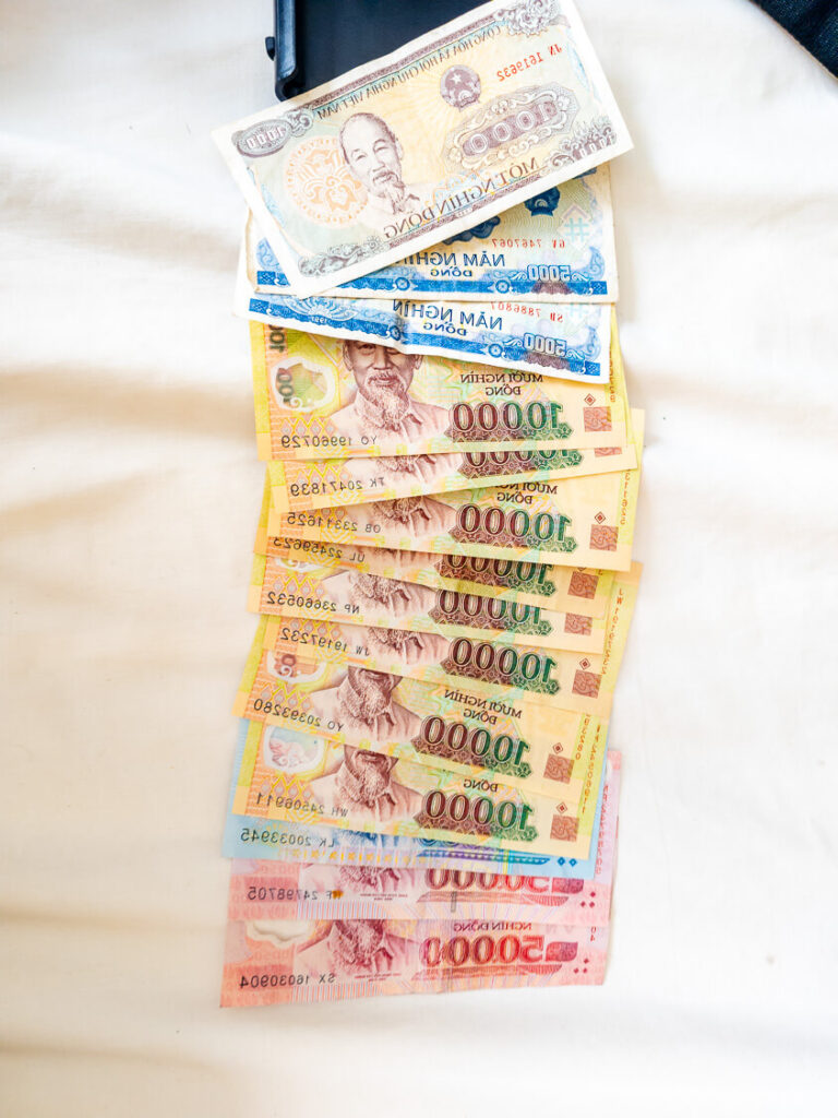 Several brightly colored Vietnamese Dong polymer bank notes fanned out by hand.
