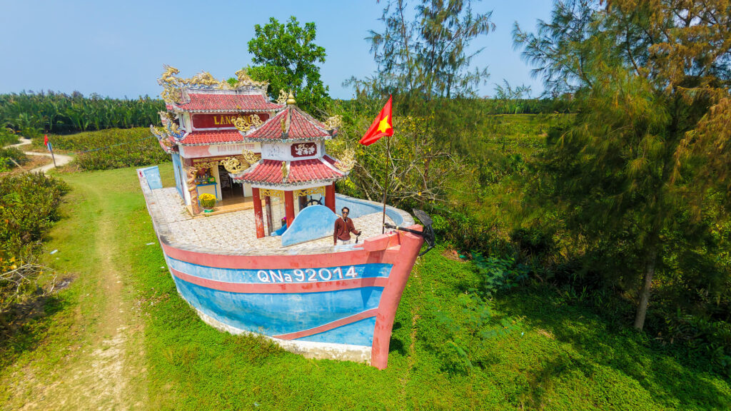Top down drone view of travel filmmaker Vishal exploring the wooden Bon Van Duy Vinh boat temple on Cam Kim Island, surrounded by incense and local offerings