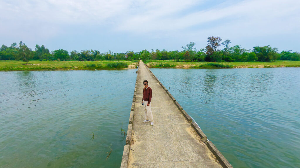 A traveler standing on the narrow Cau mang Duy Phuoc bridge that connects Cam Kim Island to the mainland over the river.