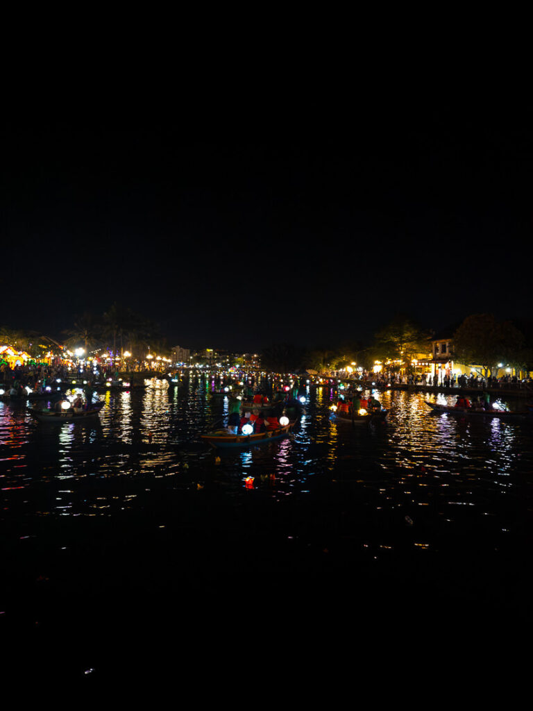 Close up of vibrant silk and paper lanterns lighting up traditional passenger boats on the river in Hoi An's Ancient Town.