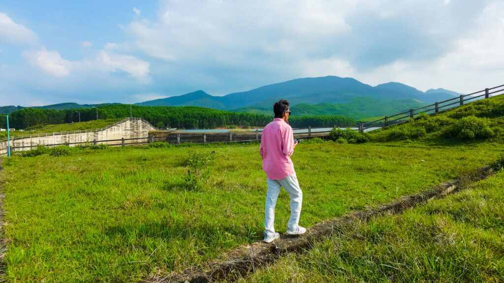 Vishal walking through the tall grass near the quiet forested edge of Khe Tan Reservoir.