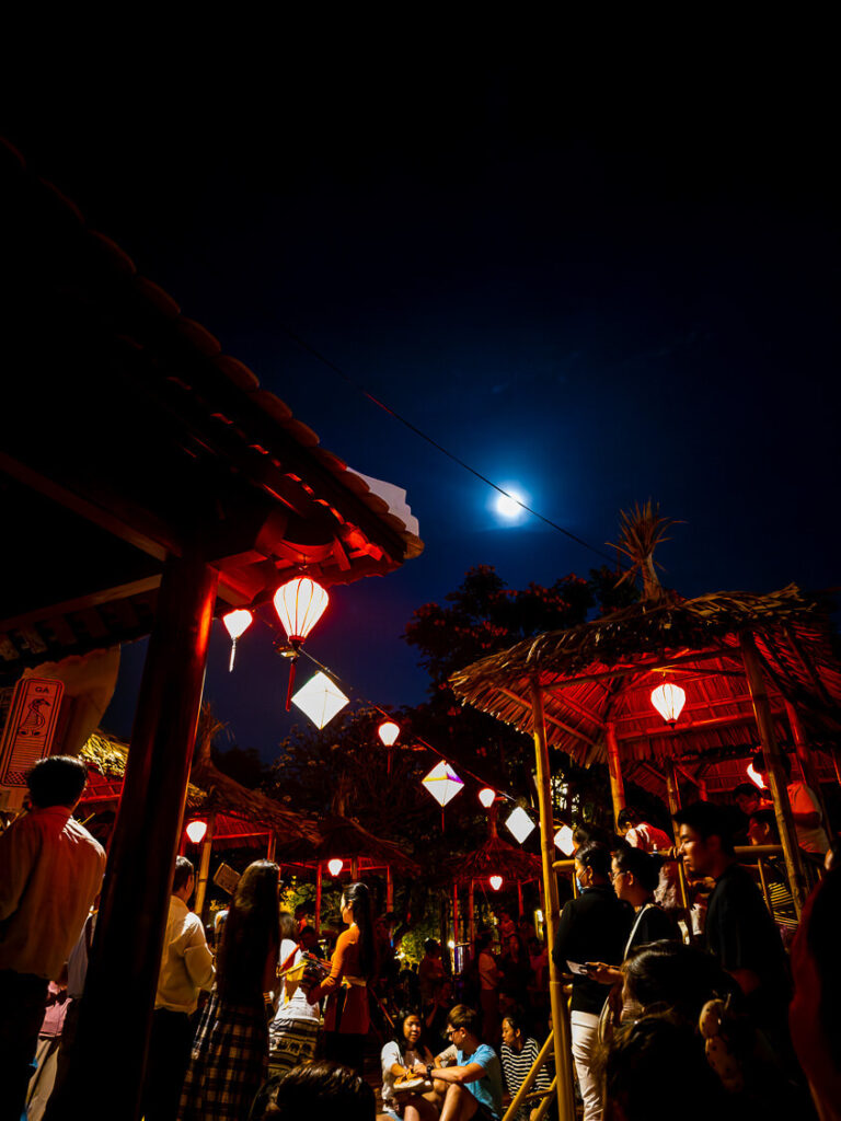 A group of locals gathered on a lantern-lit riverside street in Hoi An playing Bài Chòi, a traditional Vietnamese bingo-style game.