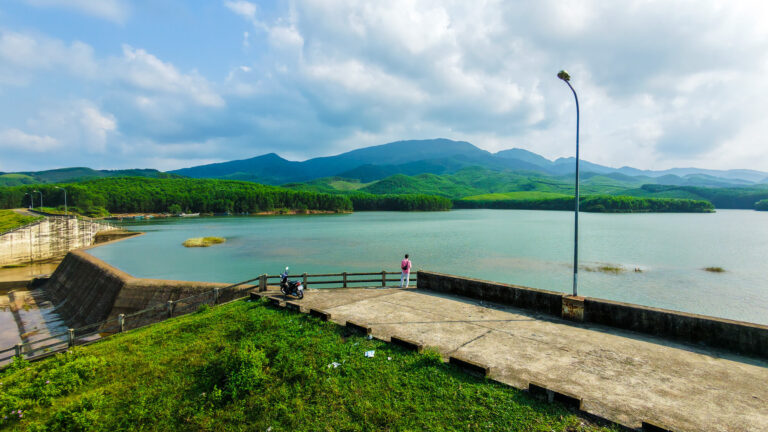 Vishal standing at the edge of the still water at Khe Tan Reservoir during a quiet day trip from Hoi An.