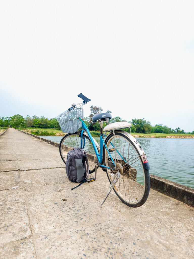 A classic rented city bicycle with a front basket parked along a quiet dirt road in the countryside.