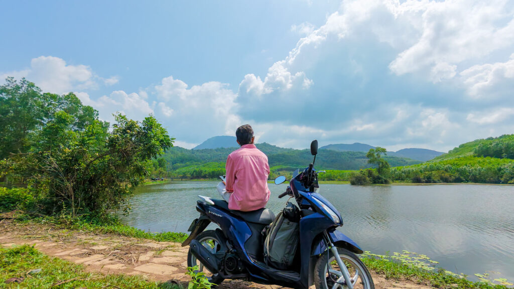 A visitor sitting on a scooter parked near the ancient Hindu temple ruins of My Son Sanctuary outside of Hoi An.