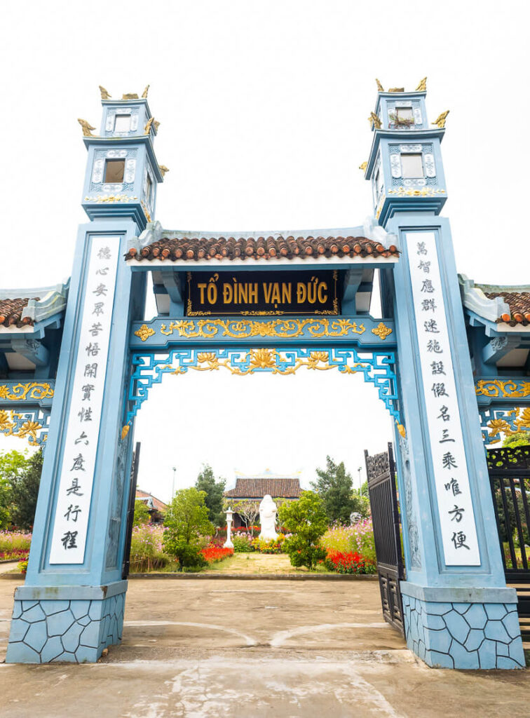 The traditional three-door entrance gate of To Dinh Van Duc pagoda, featuring curved tiled roofs and intricate carvings.