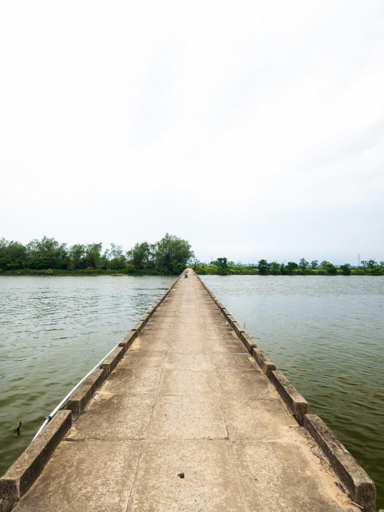 A scenic view of the narrow Cau mang Duy Phuoc bridge stretching over the water.