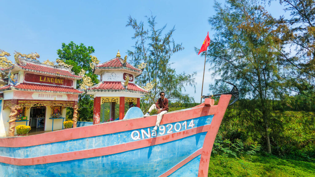 A traveler sitting quietly inside the unpolished Bon Van Duy Vinh boat temple.