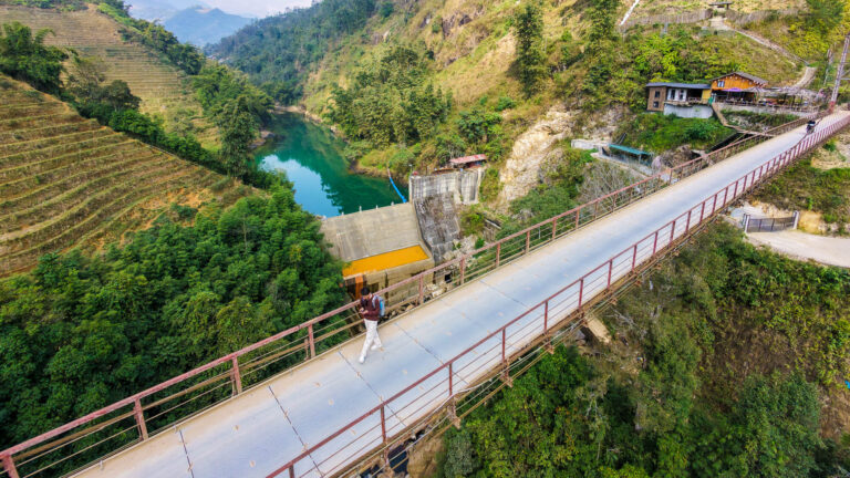 A traveler walking across a misty bridge in Sapa while checking their smartphone for the best apps for traveling in Vietnam.