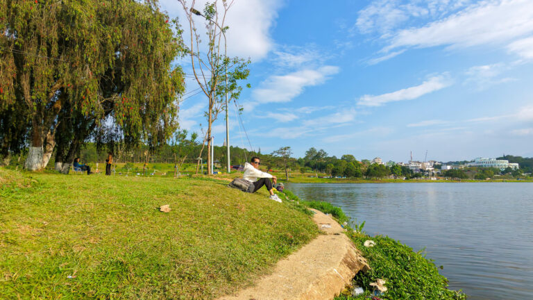 A solitary traveler sits on a bench overlooking Xuan Huong Lake in Da Lat, reflecting on unexpected challenges and common Vietnam travel mistakes, such as sudden transport shortages.