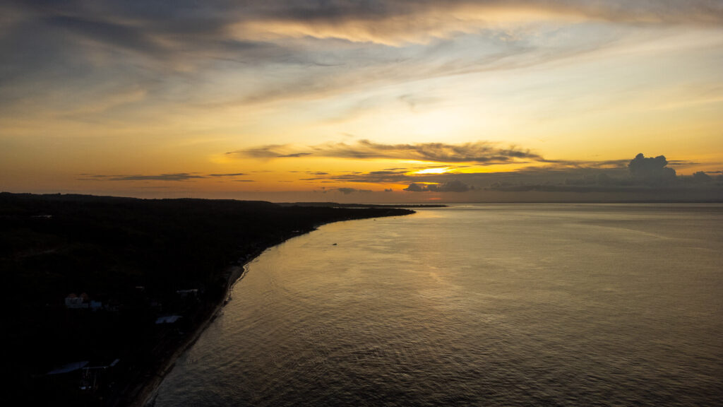How to Plan a Trip to Bali 2026: The Ultimate Regional Travel Guide 9 A stunning golden hour sunset shining over the coastline and ocean of Bali captured from above by a drone.