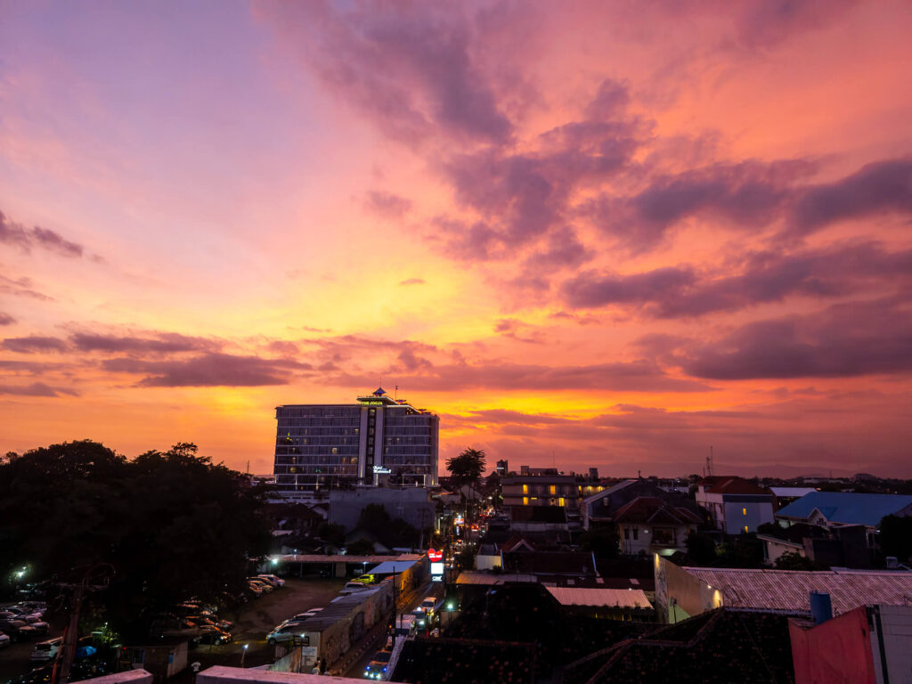 2 Days in Yogyakarta: A Slow Travel Itinerary for Central Yogyakarta 1 A colorful sunset sky over the rooftops and power lines of Central Yogyakarta, taken from a hostel terrace.