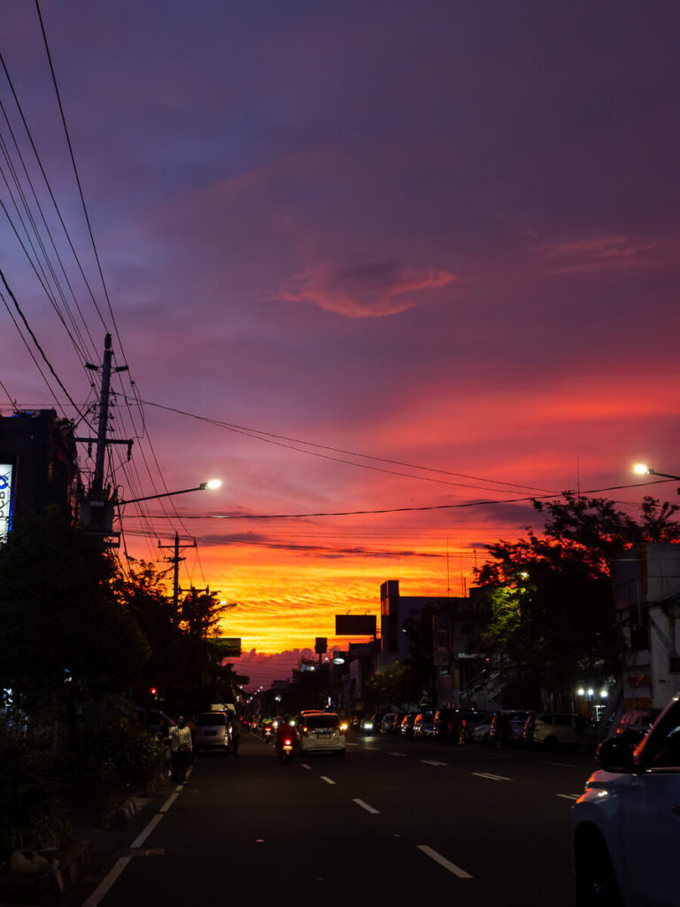 2 Days in Yogyakarta: A Slow Travel Itinerary for Central Yogyakarta 5 Warm sunset colors filling the sky above a busy street of cars and evening traffic near Tugu in Central Yogyakarta.
