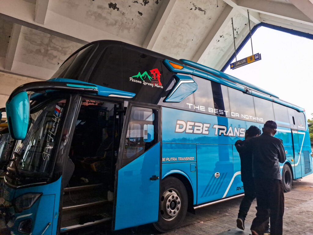 Jakarta to Bali 2026: The Perfect Guide to Flights, Buses, & Ferries 2 A Debe Trans long distance bus parked at a rest stop during the overland journey from Jakarta to Bali.