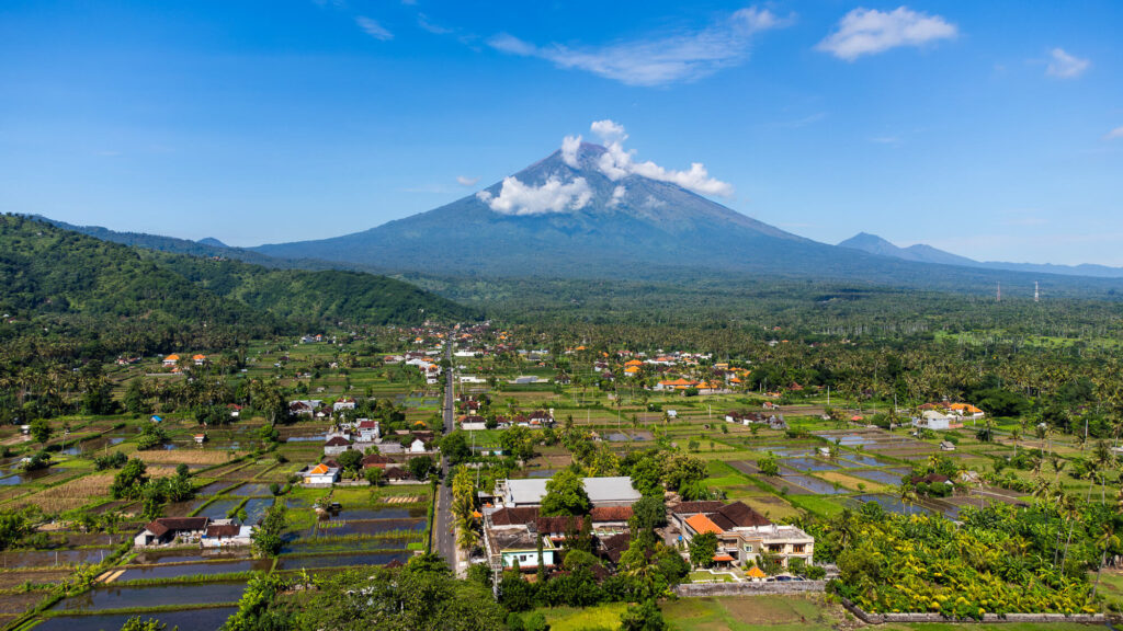 How to Plan a Trip to Bali 2026: The Ultimate Regional Travel Guide 6 Drone shot capturing the vast East Bali landscape, stretching from Amed city toward the towering peak of Mount Agung.