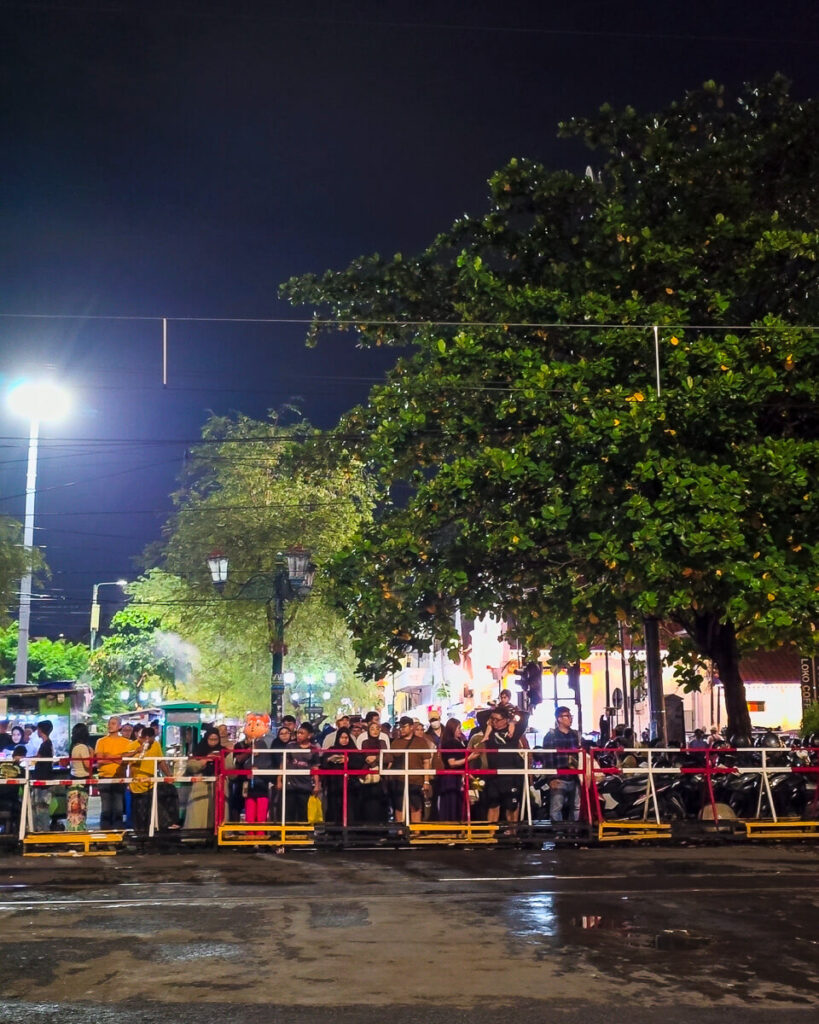 2 Days in Yogyakarta: A Slow Travel Itinerary for Central Yogyakarta 3 Local residents and motorbikes waiting patiently at a busy street-level railway crossing near Yogyakarta station.