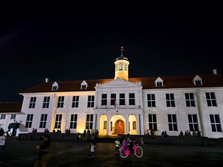 The illuminated facade of the Jakarta History Museum at night, a popular destination after traveling from Yogyakarta to Jakarta.